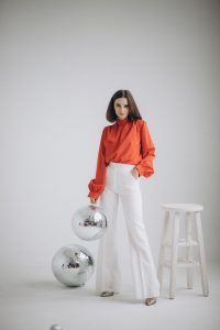 Smart Casual Style Guide for Women Stylish woman in orange and white attire with disco balls in a studio setting.