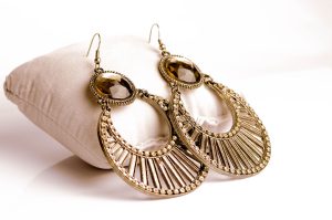 Trends in Women wear in 2026 Close-up of intricately designed gold earrings resting on a plush white pillow for luxurious jewelry presentation.