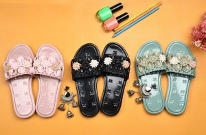 Smart Casual Style Guide for Women Vibrant floral slippers with nail polish and earrings on a yellow background. Perfect studio shoot for lifestyle products.