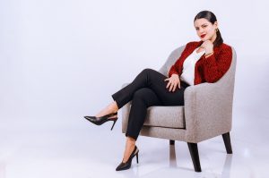 How to Choose Outfits You Can Wear on Different Occasions Fashionable woman in a red jacket and heels sitting on a stylish armchair against a white background.