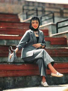 Trends in Women wear in 2026 Elegant woman in a grey suit sitting on steps outdoors, exuding fashion and confidence.