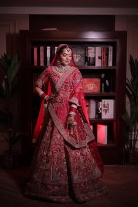 How to Choose Outfits You Can Wear on Different Occasions Indian bride in luxurious red lehenga with intricate embroidery inside a library setting.