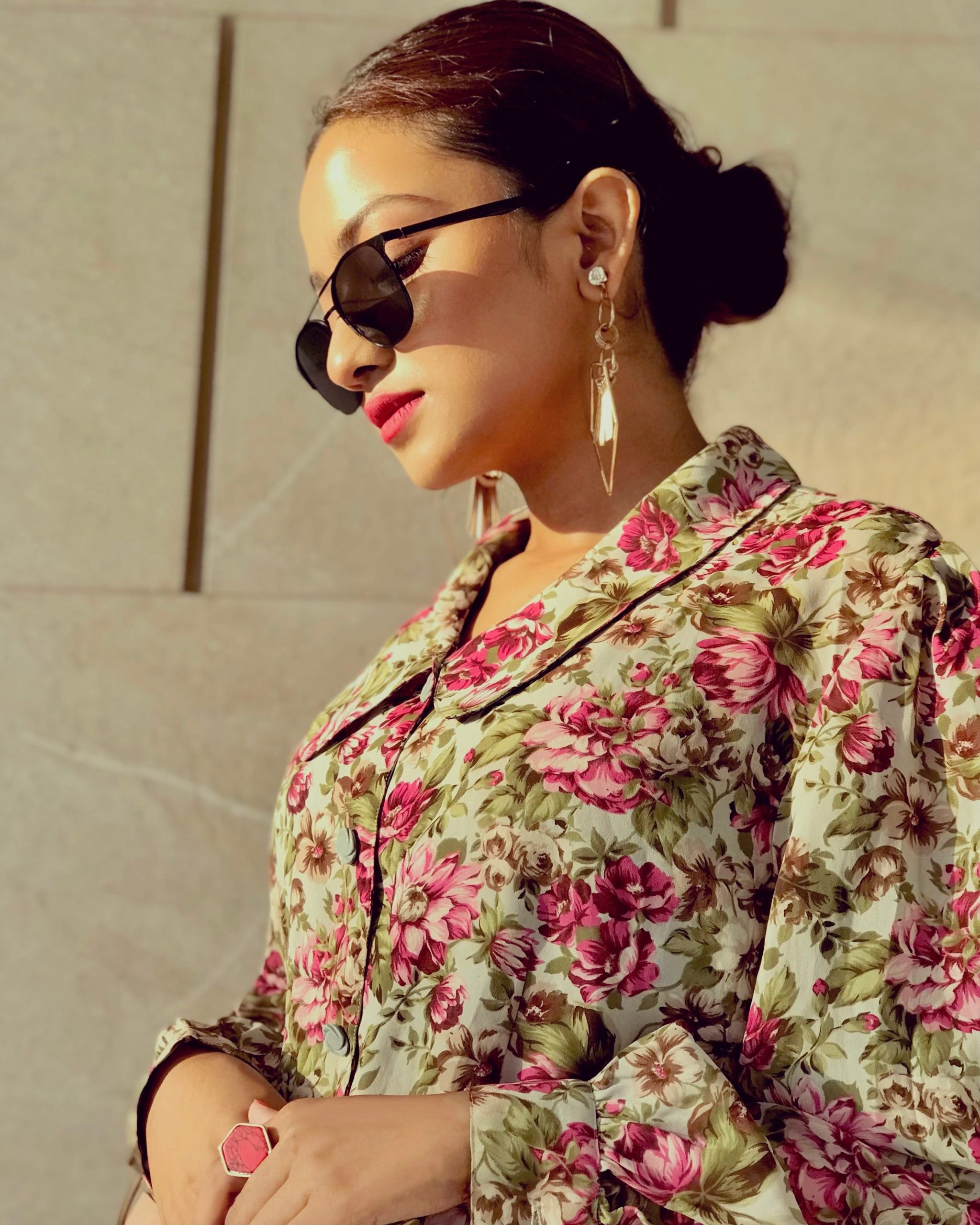 Stylish woman wearing floral top and sunglasses, exuding modern elegance.